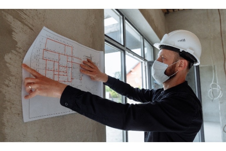 Man in hard hat holding up construction plan