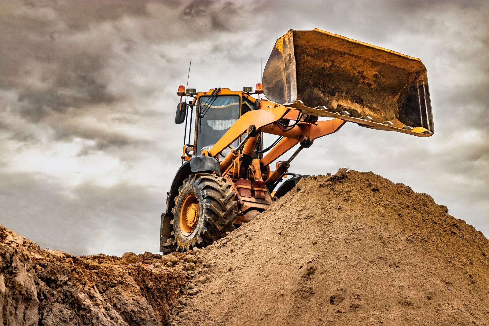 Powerful wheel bulldozer on top of rubble pile working on quarry site