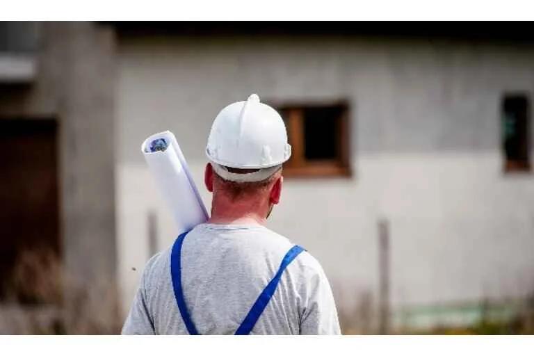 Builder looking at a house holding construction plans