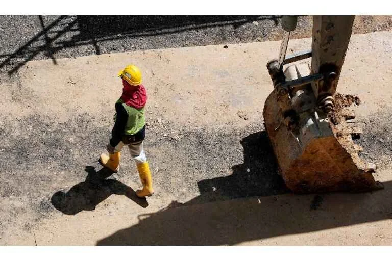 Builder walking beside digger
