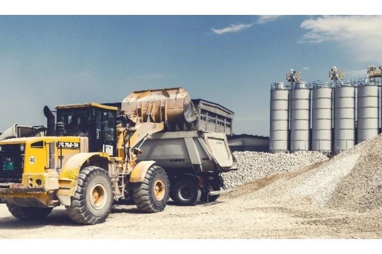 Digger offloading into truck at construction site
