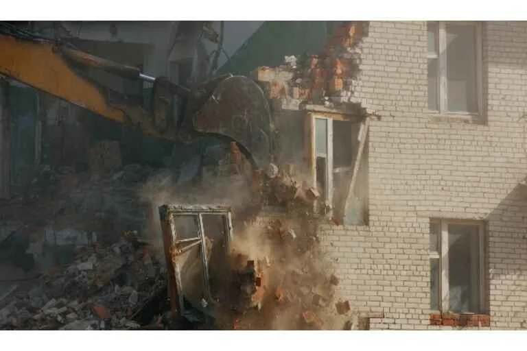 Digger pulling down bricks
