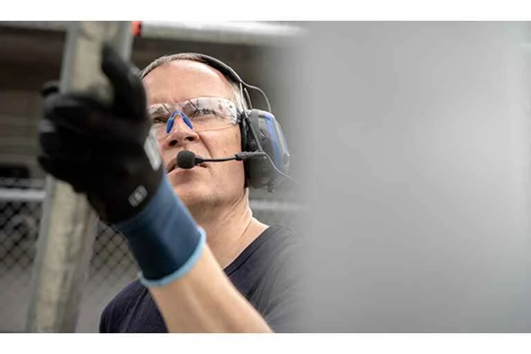 Man working on construction site wearing ear defenders and goggles.