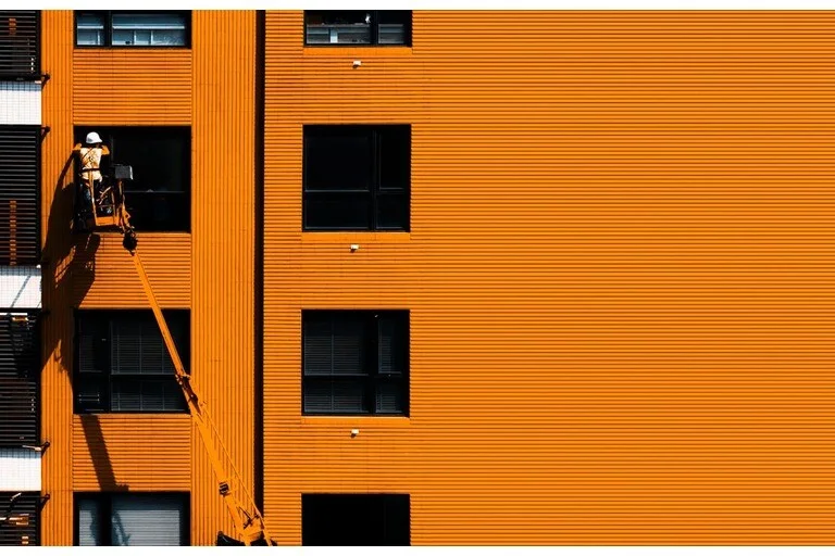 Person working in a cherry picker on orange building