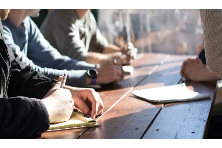 People sat at a table having a meeting and writing notes