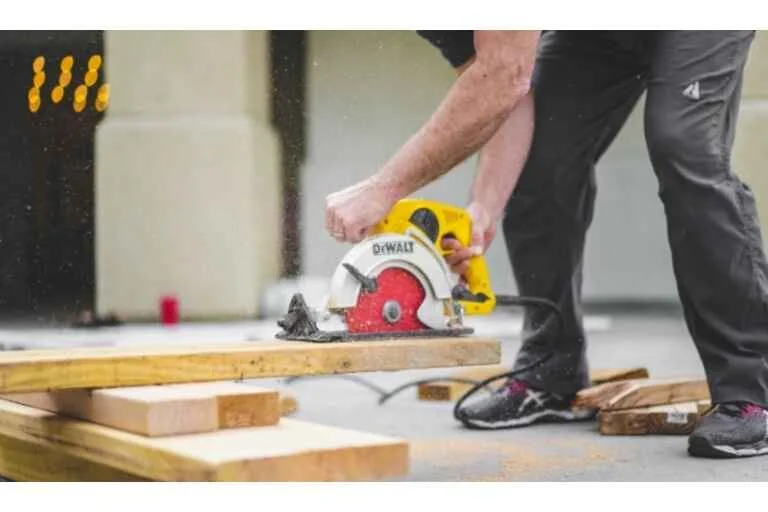 Man in black trousers cutting wood with plunge saw