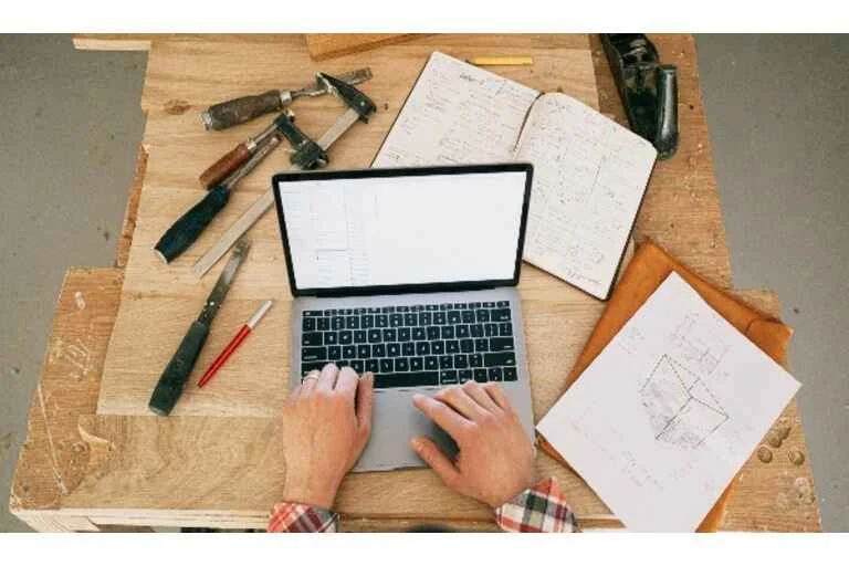 Man typing on laptop on a wooden table