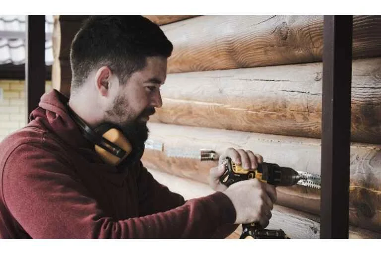 Man drilling through wooden wall