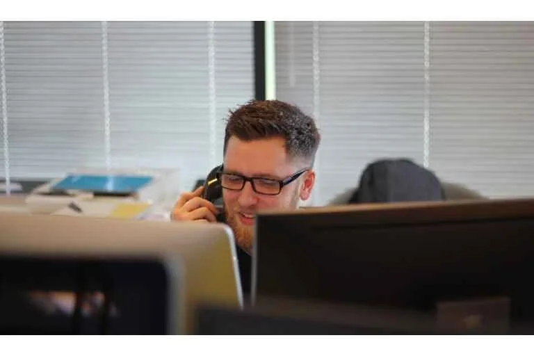 Man talking on the phone in front of desktop