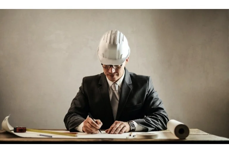 Man wearing hard hat and suit writing construction plan