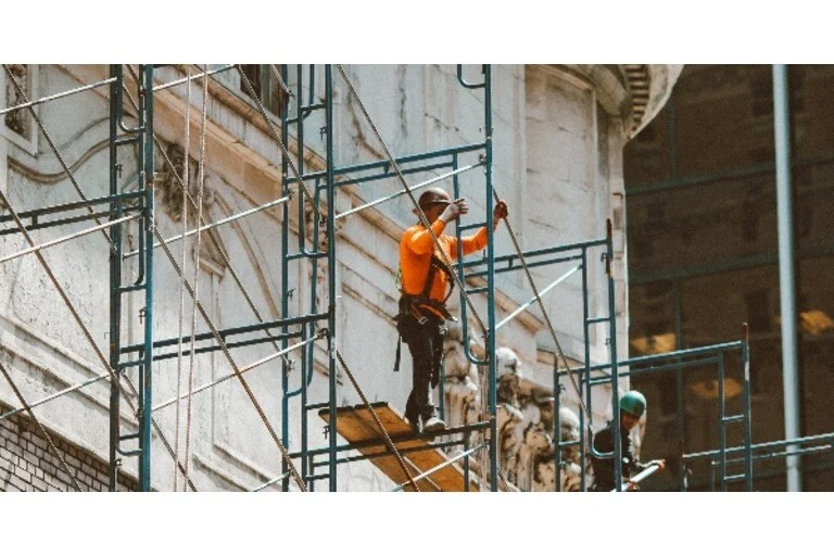 Man wearing orange uniform working on scaffold