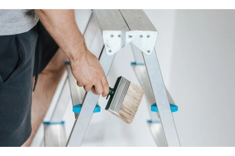 Person stepping on ladder holding paint brush