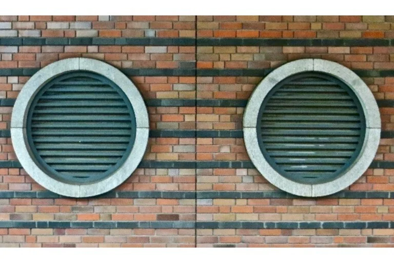 Two round, green ventilators on the side of brick building
